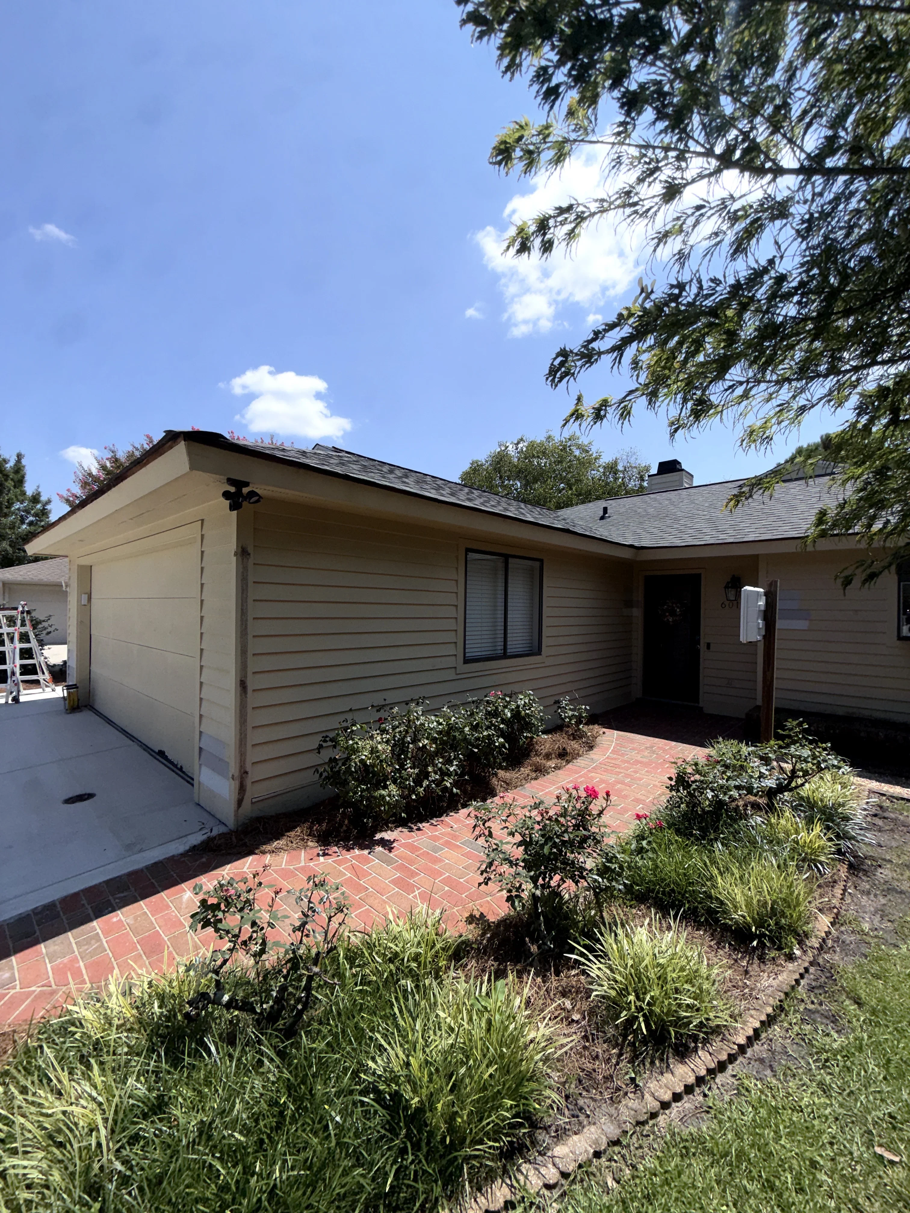 Horizontal vinyl siding home with brick paver walkway and landscaped planting beds
