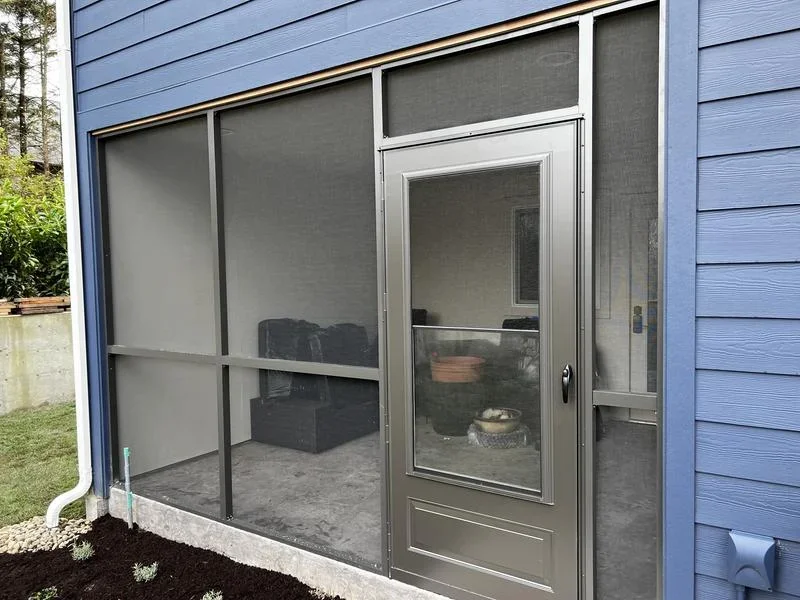 Aluminum-framed screened porch with gray mesh panels and matching entry door