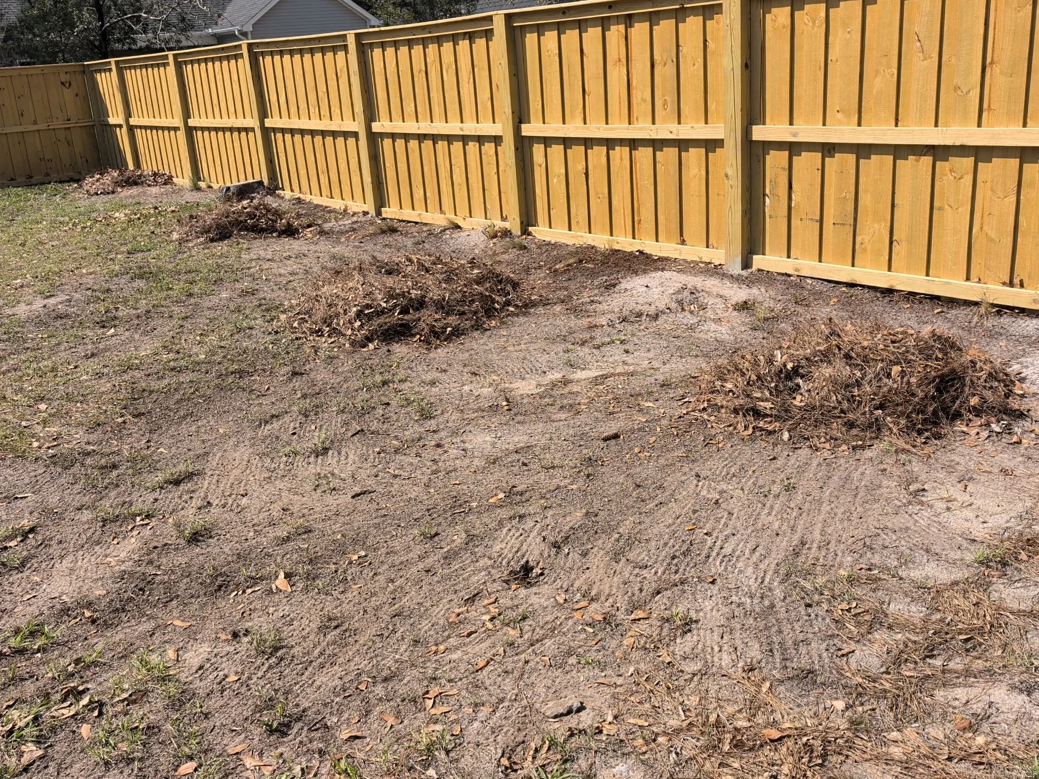 New wood privacy fence with vertical boards and metal frame supports installed along residential property line