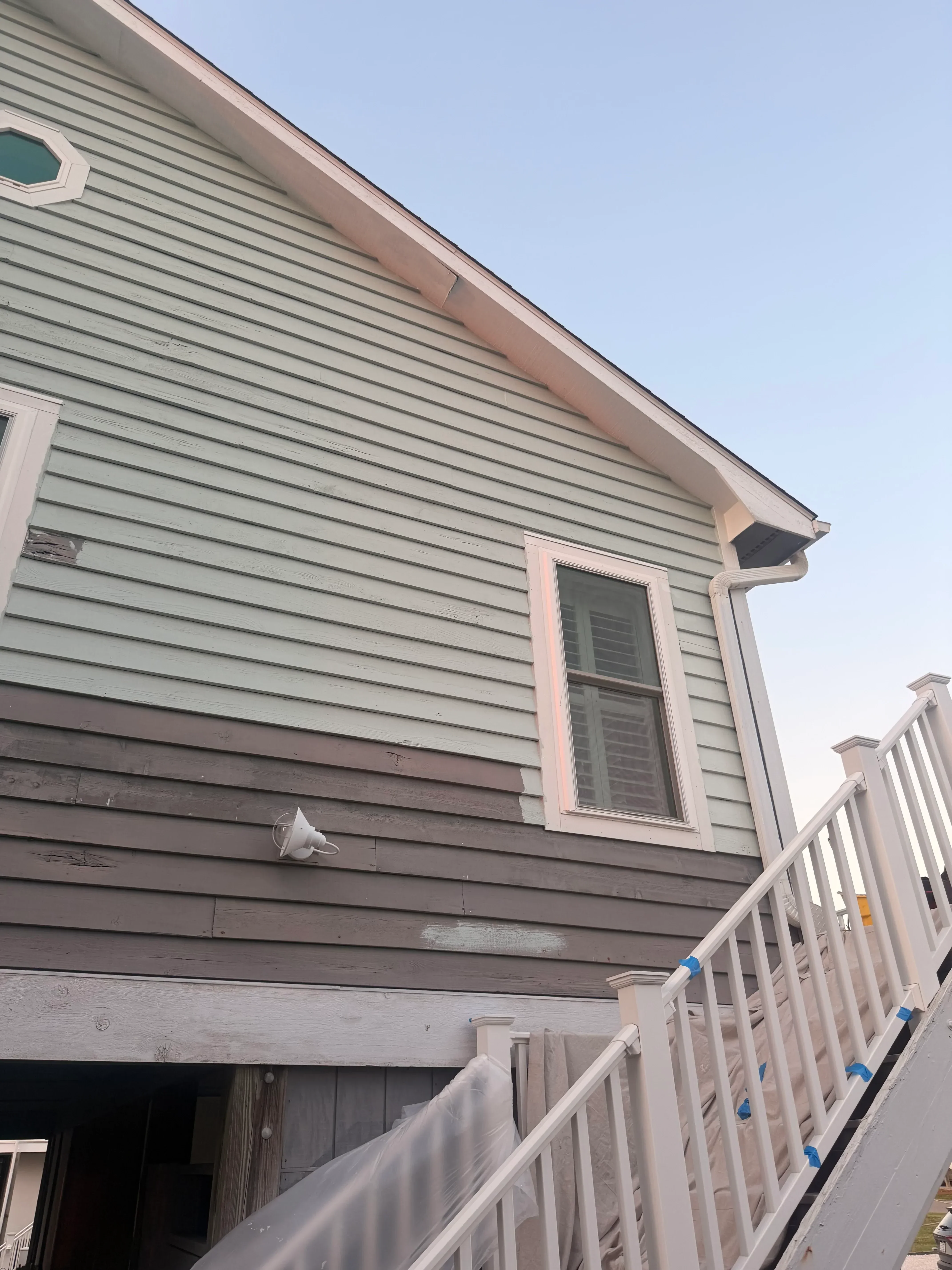 Vertical metal siding with white trim, window, and soffit installation on residential exterior