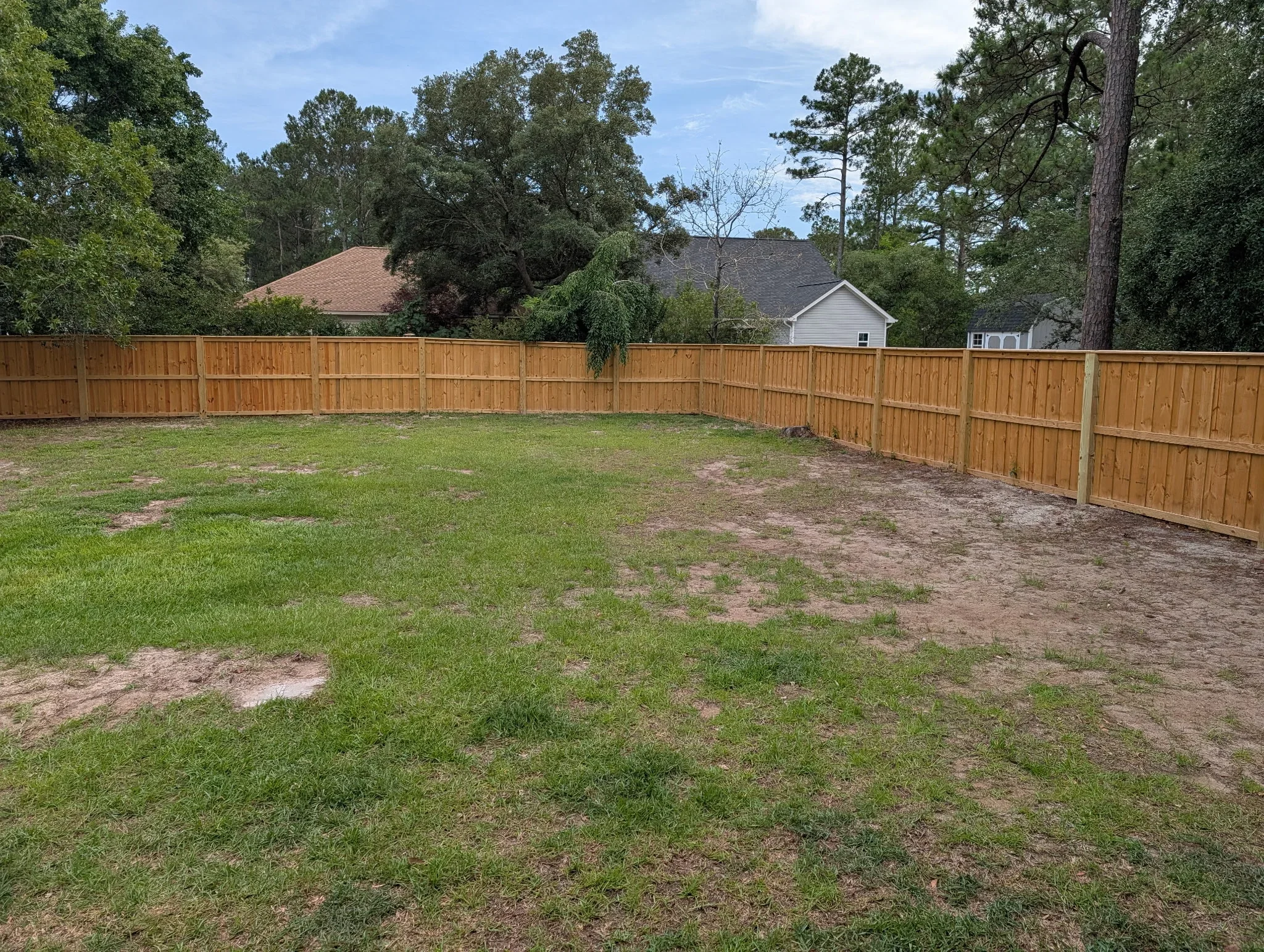 Cedar wood privacy fence with vertical boards and metal posts installed around residential backyard